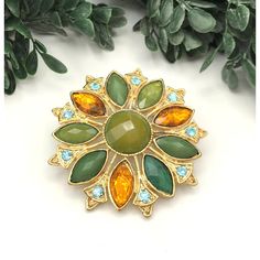 Elegant vintage brooch featuring a floral design with green and oragne rhinestones. Ideal for adding a touch of sophistication to your attire. * Gold-tone metal * Green and orange rhinestones * Floral design * Secure pin clasp * Measures approximately 2 inches in diameter item# 2A24049 Gold-tone metal shows minor wear consistent with vintage age. Measures approximately 2 inches in diameter. Gently loved Thank you for visiting our shop... Green Jeweled Brooch For Gift, Green Jeweled Brooches As Gift, Floral Brooch, Vintage Brooch, Women Accessories Jewelry, Gold Tone Metal, Vintage Brooches, Green And Orange, American Vintage