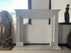 a white marble fireplace surround with statues around it