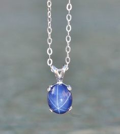 "A stunning new necklace made using a star sapphire gemstone. The sapphire is oval shaped and cabochon cut. It is excellent quality and set into a sterling silver prong setting. Lab grown Sapphire measures 10mm tall (just under 1/2\") while entire pendant is roughly 1/2\" tall. It hangs from sterling silver chain. Please choose desired chain length at checkout. Please see matching ring and earrings here: https://www.etsy.com/shop/hangingbyathread1?ref=search_shop_redirect&search_query=star+s Star Shaped Sapphire Jewelry Gift, Sapphire Jewelry With Oval Cabochon For Gift, Oval Sapphire Cabochon Necklace, Oval Sapphire Necklace With Cabochon Cut, Celestial Oval Sapphire Jewelry, Oval Sapphire Celestial Jewelry, Star Sapphire Gemstone, Sapphire Pendant Necklace, Oval Pendant Necklace