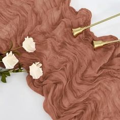 some white flowers and gold hair pins on a brown cloth with long, wavy hair