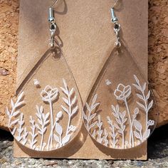 a pair of earrings with flowers and leaves etched on them