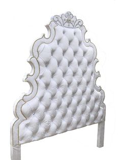 an upholstered white headboard with gold trimmings and pearls on it