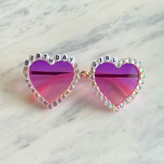 a pink heart shaped sunglasses with the words birthday girl written on it's side