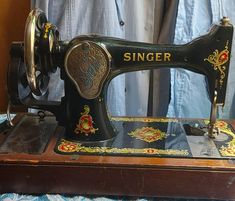 an old sewing machine sitting on top of a wooden table next to a blue curtain