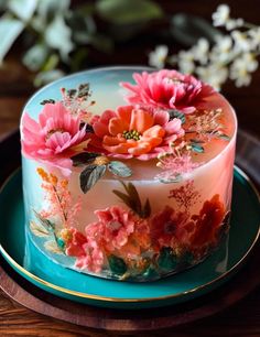 a cake decorated with pink flowers on a blue plate and gold rimmed platter