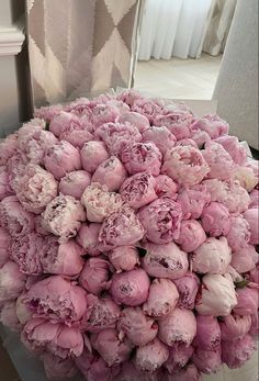 a large bouquet of pink peonies on a table in front of a window