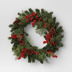 a christmas wreath with red berries and pine cones