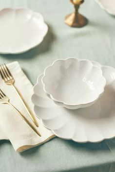 white plates and silverware on a blue table cloth with gold utensils in the background