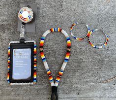 an assortment of beaded bracelets and ear rings on the ground next to a cell phone