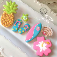 decorated cookies on a white platter with pineapples, flip flops and flowers