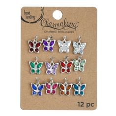 six butterfly charms with different colors and sizes on the back of a card board,