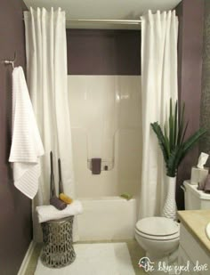 a white toilet sitting next to a bath tub in a bathroom