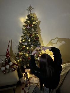 a woman decorating a christmas tree in her living room