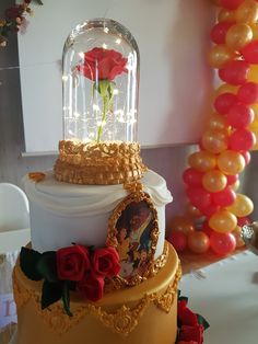 a beauty and the beast themed birthday cake with roses on top, surrounded by balloons