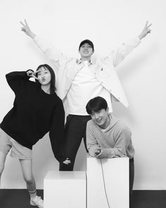 three people standing on top of two boxes with their arms in the air and smiling