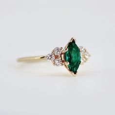 an emerald and diamond ring on a white background