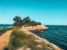 an island in the middle of the ocean with grass growing on it's sides