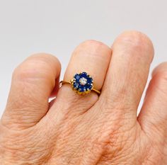 Give yourself a treat with this dainty little tulip ring in 18k yellow gold that's a timeless classic. Flowers are beautiful so why not put one on your finger? This ring weighs 3.4g and is a size 4.5. Studded with beautiful sapphires and a diamond in the middle, sapphires weighing 0.50 carats and the diamond weighing 0.06 carats, this ring is exactly what you need for your jewelry desires. Yellow Gold Solitaire Diamond Flower Ring, Classic 14k Gold Flower Ring With Gemstone, Brilliant Cut Sapphire Birthstone Ring In Yellow Gold, Yellow Gold Sapphire Birthstone Ring With Brilliant Cut, Elegant Yellow Gold Flower Ring With Birthstone, Yellow Gold Round Flower Ring For Proposal, Yellow Gold Flower Ring For Proposal, Classic Sapphire Birthstone Ring For Proposal, Classic 14k Gold Sapphire Ring For Proposal