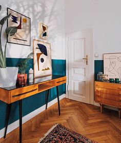 a living room with blue walls and wooden floors, artwork on the wall above a console table