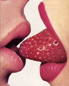 a close up of a person kissing a strawberry