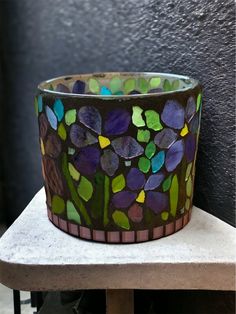 a pot with flowers painted on it sitting on a table next to a wall and some shoes