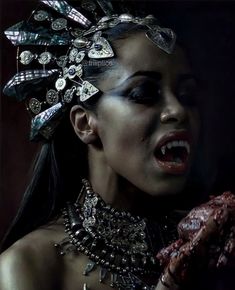 a woman with jewelry on her face and hands in front of her face, covering her mouth