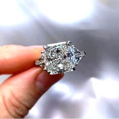 a woman's hand holding an old - fashioned diamond ring with three stone sidestones