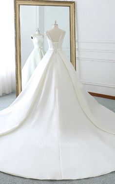 a white wedding dress on display in front of a mirror