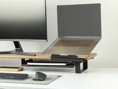 a computer desk with a laptop, keyboard and mouse on it in front of a monitor