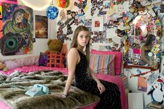 a woman sitting on top of a bed in a room filled with pictures and decorations