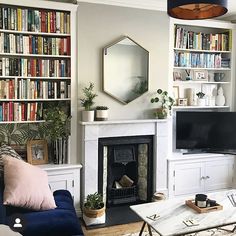 a living room filled with furniture and a fire place in front of a book shelf