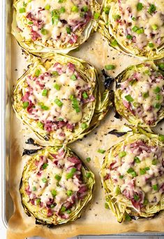 artichokes stuffed with cheese and green onions in a baking dish on a sheet pan