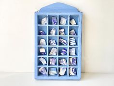 a blue shelf filled with lots of different types of ceramic items on top of a white table