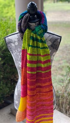 a multicolored knitted scarf hanging on a mannequin