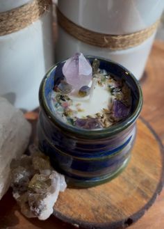 a candle is sitting on a table next to some rocks and glass jars with crystals in them