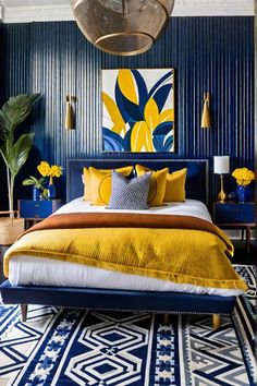 a bedroom with blue walls and yellow bedding, artwork on the wall above it