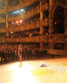 a woman standing on top of a stage in front of an auditorium filled with people