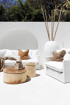 an outdoor living area with white furniture and pillows