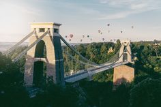 many hot air balloons are being flown over the suspension bridge in bristol, england as the sun sets