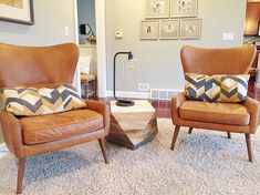 two brown chairs sitting next to each other on top of a carpeted living room floor