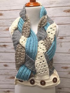 a white mannequin wearing a blue and gray knitted scarf