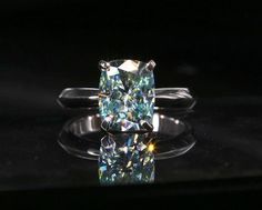 a fancy ring with a cushion cut diamond in the center on a black background photo