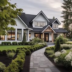 a white house with lots of windows and bushes in front of the entrance to it