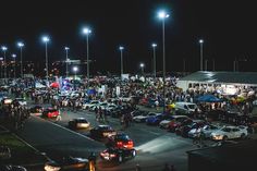 a large group of people standing on the side of a road next to parked cars