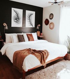 a large bed sitting in a bedroom next to a window with pictures on the wall