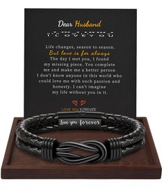 a black leather bracelet with the message dear husband on it and a wooden plaque in front