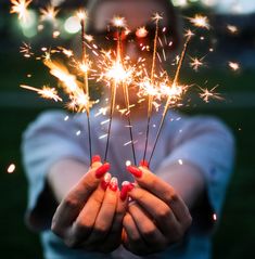 a woman holding sparklers in her hands