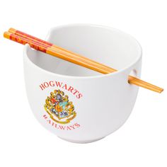 two chopsticks sticking out of a harry potter mug with the hogwart's crest on it