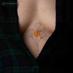 a woman's chest with a flower tattoo on her left side, and an orange circle in the center