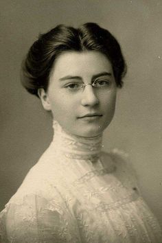 an old black and white photo of a woman with glasses on her head, wearing a lace dress